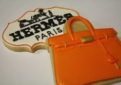 an orange purse cookie next to a sign that says herms paris with a handbag on it