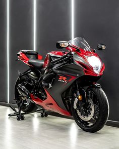 a red and black motorcycle parked in front of a wall