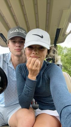 a man and woman sitting in the back of a golf cart with their hats on