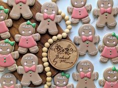 ginger cookies decorated with pink and green bow ties are on a wooden platter next to a plaque that says baked by mom