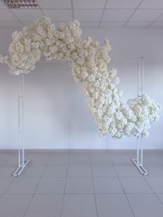 white flowers are arranged on metal poles in an empty room