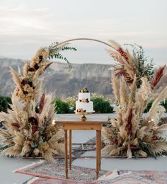 an outdoor wedding setup with pamodia and cake on the table, surrounded by greenery