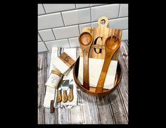 two wooden utensils are sitting in a bowl next to some napkins and spoons