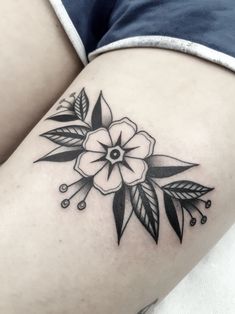 a black and white flower tattoo on the thigh