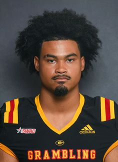 a man with long hair wearing a black and yellow football uniform is looking at the camera