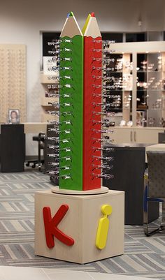 a colorful pencil holder sitting on top of a wooden block in an office setting with chairs and desks behind it