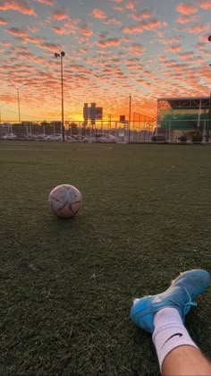 a soccer ball sitting on top of a field next to a person's feet