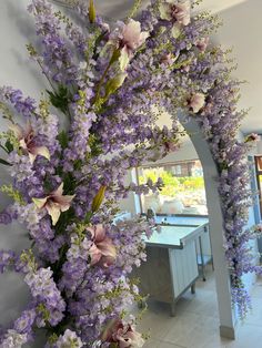 purple and white flowers are arranged on the wall