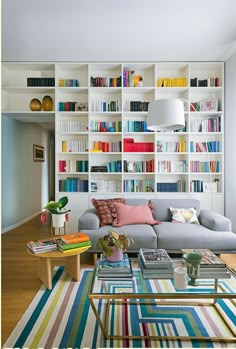 a living room filled with furniture and lots of books on the shelves in front of it