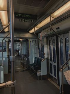 the interior of a train with many seats and railings on both sides, along with an exit sign