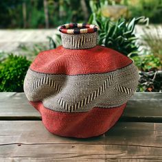 a red vase sitting on top of a wooden table