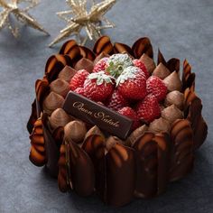 a chocolate cake with strawberries in the center on a gray surface next to star decorations