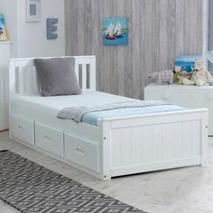 a white bed sitting in a bedroom on top of a wooden floor next to a window