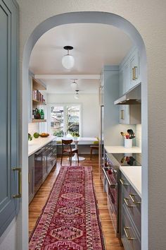 an archway leading to a kitchen with a rug on the floor in front of it