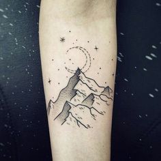 a tattoo on the arm of a person with mountains and stars in the sky above them