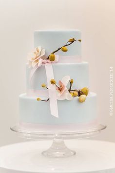 a three tiered blue cake with flowers on it