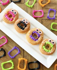 three donuts with fake eyes and googly eyes are on a plate surrounded by plastic letters