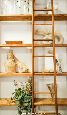 an old wooden ladder leaning up against a wall filled with vases and other items