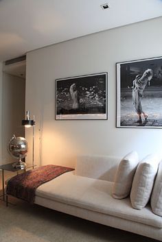 a living room with white couches and pictures on the wall above them in black and white