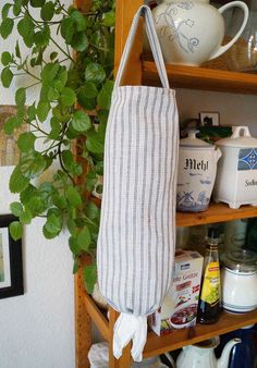 a bag hanging from a shelf next to a potted plant and other kitchen items