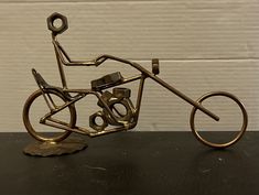 a metal sculpture of a man riding a bike on top of a black table next to a white wall