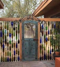 a wooden gate with glass bottles hanging from it's sides and a green door