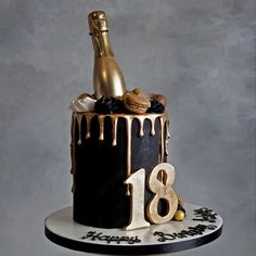 a black and gold birthday cake with a bottle of champagne