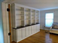 a living room with white bookcases and wood floors