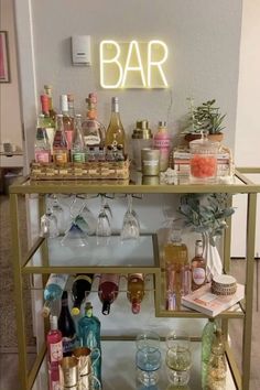 a bar cart filled with liquor bottles and glasses next to a neon sign that says bar