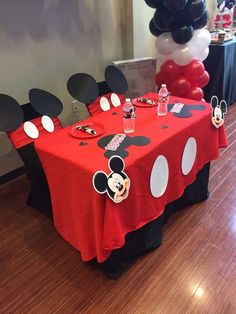 a mickey mouse themed party with balloons and table cloths on the floor in front of it