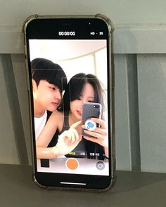 a cell phone hanging from the side of a wall with an image of two people on it