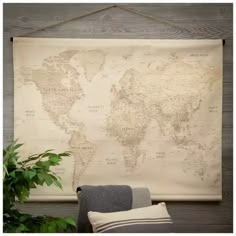 a large map hanging on the wall next to a chair and potted plant in front of it