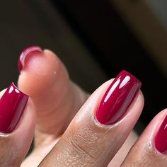 a woman's hand with a red manicure and nail polish on her nails