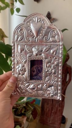 a person holding up an ornate silver frame