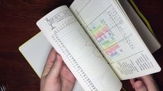 a person is holding an open notebook with numbers and graphs on it, while sitting at a table