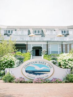 the sign for chatham bar and grill in front of a large building with flowers around it