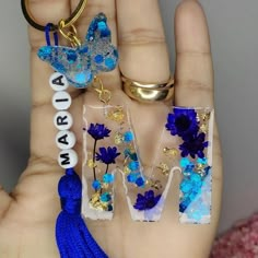 two pieces of glass with flowers and letters on them are being held by a person's hand