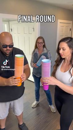 two women and a man are in the middle of a dance class holding large, colorful objects