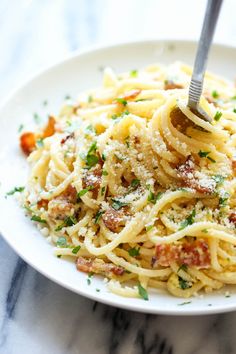 a white plate topped with pasta covered in sauce and parmesan