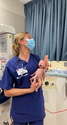 a woman in scrubs holding a baby doll