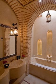 a bathroom with two sinks and a bathtub in the middle of an arched wall