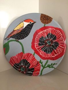 a decorative plate with birds and flowers painted on the front, sitting on a counter