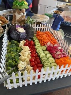 an assortment of vegetables in a white basket on a table with other food items around it