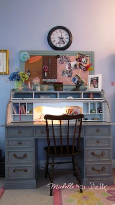 a desk with a chair, clock and pictures on the wall