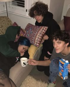 three people sitting on a couch drinking coffee