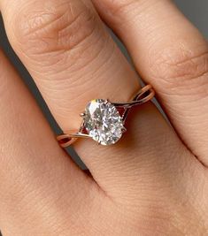 a woman's hand with a diamond ring on top of her finger and an engagement band