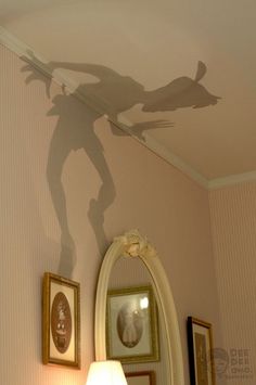 the shadow of a man is cast on the wall above a mirror in a bedroom