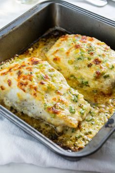 two pieces of chicken in a pan with cheese and broccoli on the side