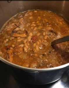 a pot filled with beans and meat on top of a stove