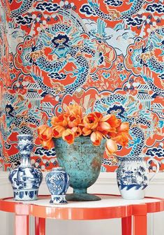 three vases with flowers in them sitting on a table next to a wallpaper